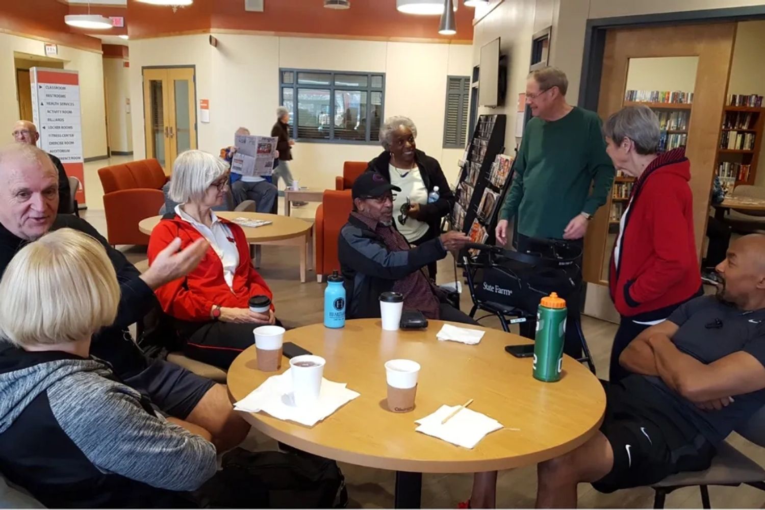 A group of ARC members chats at a table in Bonnie's Cafe at ARC in Normal while they enjoy coffee.