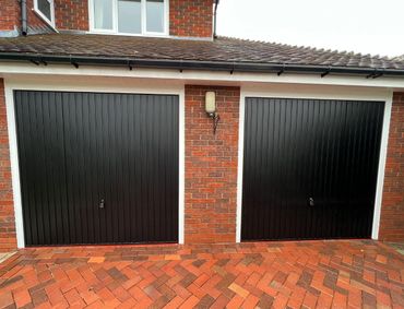 2x Black vertical canopy hormone garage doors with white upvc surround