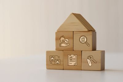 Wooden blocks with real estate icons arranged like a house.