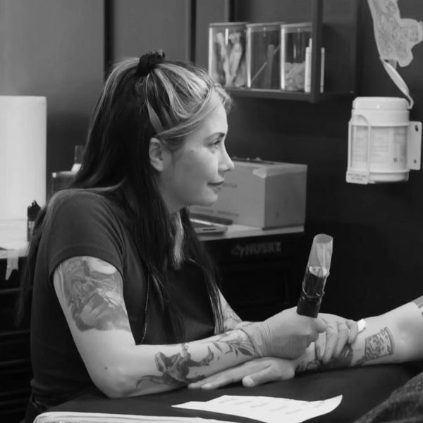 Tatuadora concentrada trabajando en un tatuaje.