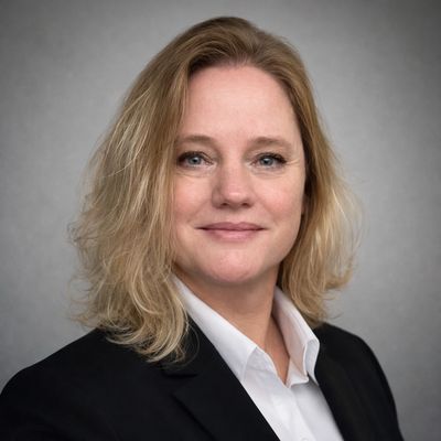 Professional portrait of a confident woman with blonde hair in business attire.