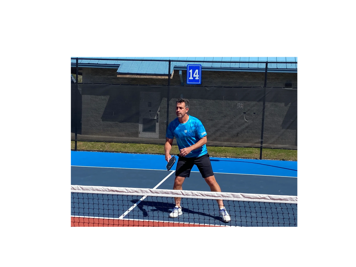 Man ready to play pickleball on an outdoor court with a blue surface.