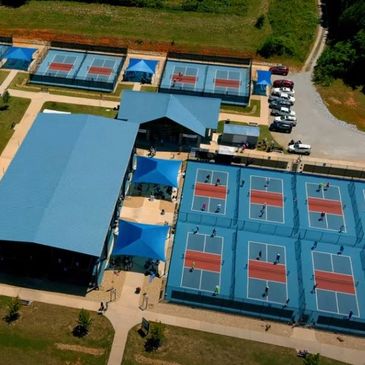 Aerial view of a sports complex with multiple tennis courts and buildings.