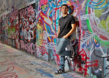Person standing against colorful graffiti wall.