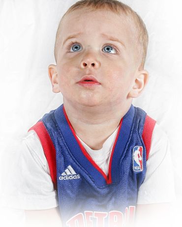 Curious toddler in a blue NBA jersey looking up.