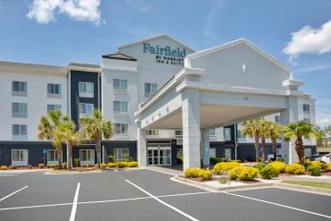 Exterior view of Fairfield by Marriott hotel with palm trees.