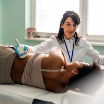 Doctor performing ultrasound on pregnant woman.