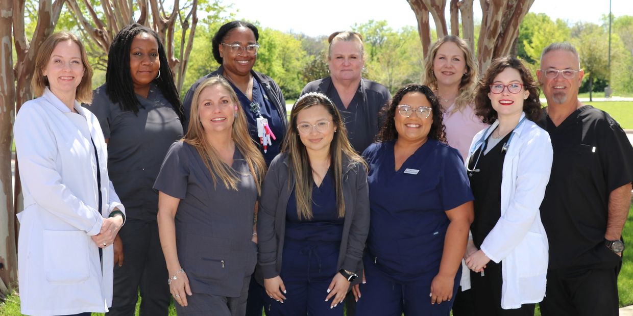 Group of healthcare professionals posing outside on a sunny day.