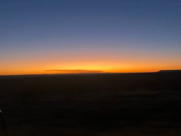 A serene sunset with a gradient sky over a dark horizon.