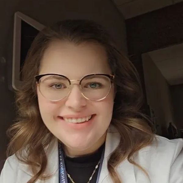 Smiling woman with glasses and wavy hair.