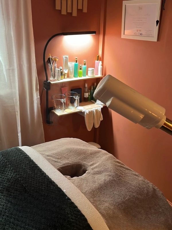 A cozy spa room with a treatment bed and skincare products.