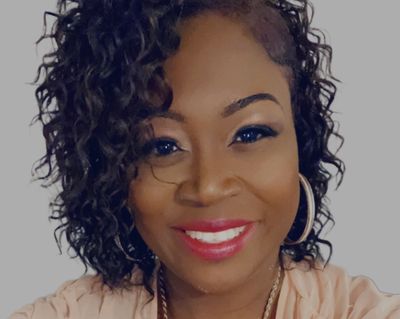 Smiling woman with curly hair and hoop earrings.