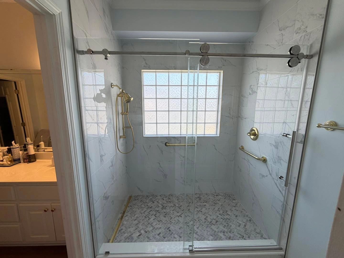 Modern walk-in shower with glass doors and marble tiles.