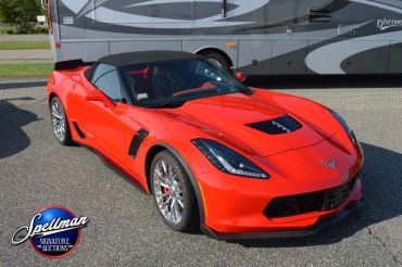 Bright red Chevrolet Corvette convertible parked on pavement.