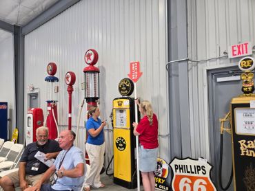 People interact with vintage gas pumps and signs in a museum-like setting.