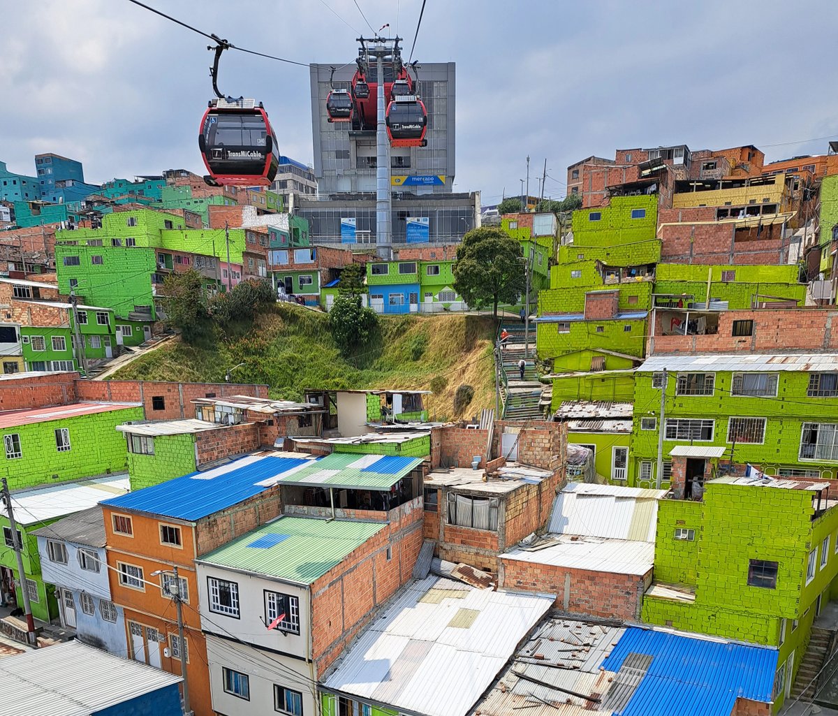 Colorful hillside neighborhood with cable cars in motion.