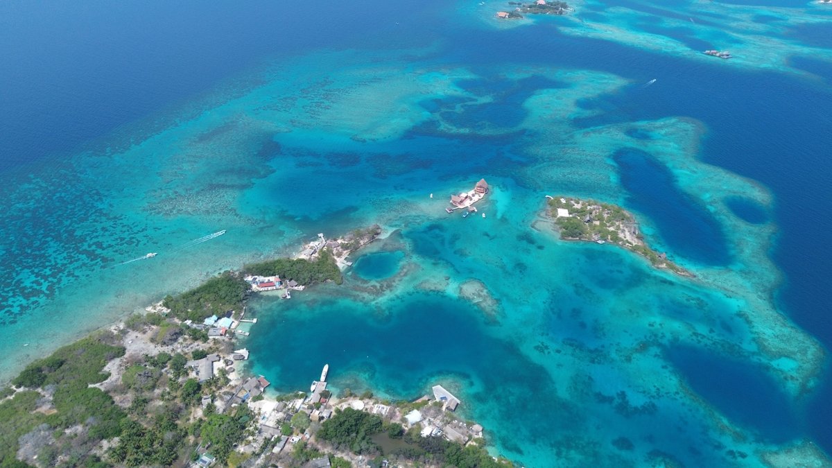 Aerial view of turquoise waters and small islands with buildings and boats.