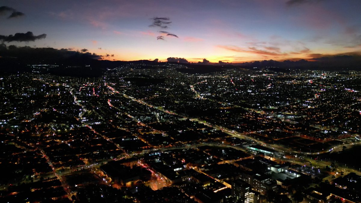 Cityscape at dusk with streets illuminated and a colorful sky.