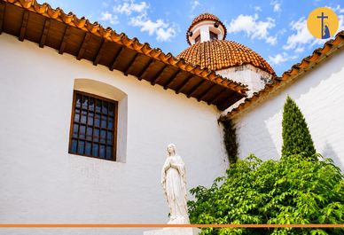 Estatua delante de iglesia con cúpula y cielo azul.