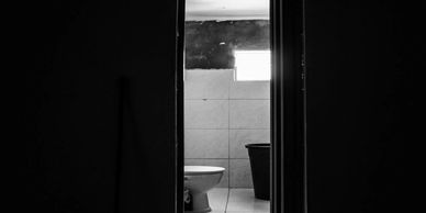 A dimly lit bathroom seen through a narrow door opening.