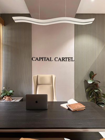 Modern office desk with laptop and notebooks, featuring a beige chair and plants.