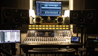 Professional audio mixing setup with multiple monitors and control panels.