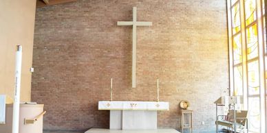 Photo of the altar and the cross above, along with the paraments in white.