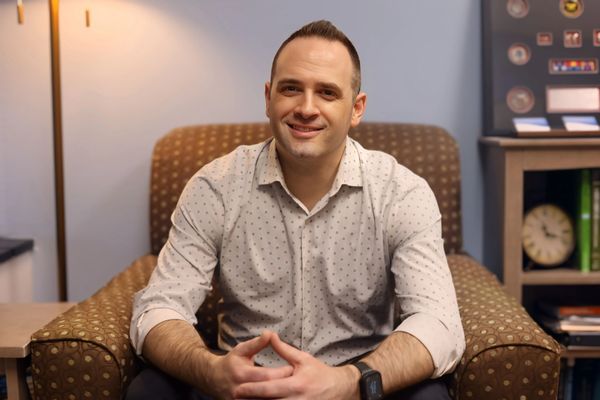 Man sitting on a brown armchair smiling.