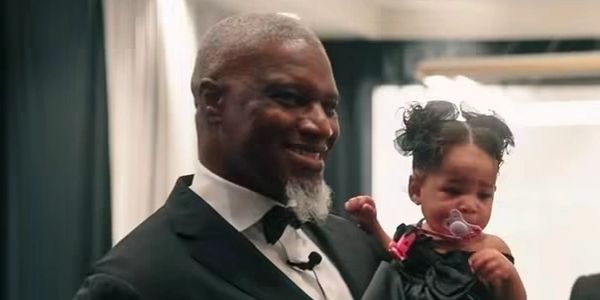 Man smiling holding a baby girl with a pacifier.