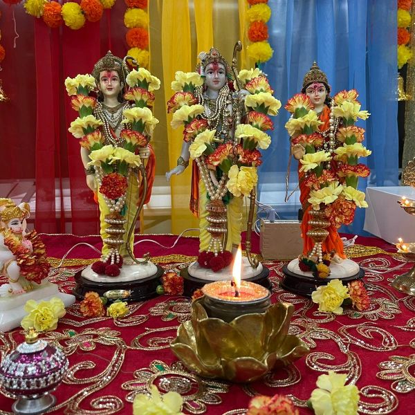 Decorated Hindu deities with flowers and a lit lamp.