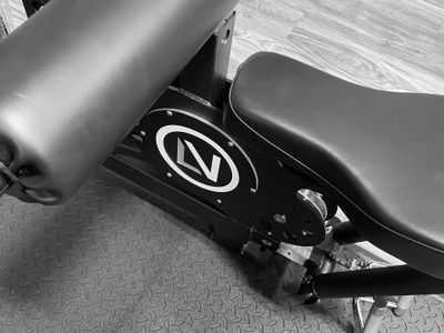 Close-up of a gym bench with padded support and a logo on the frame.