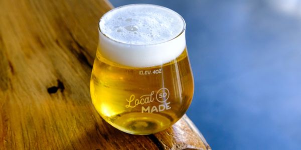 A glass of beer with foam on a wooden surface.