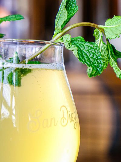 A refreshing yellow drink garnished with fresh mint leaves in a glass.