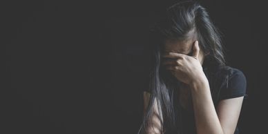 woman covering her face in a dark room