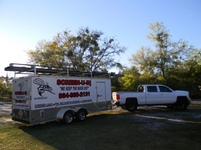 White truck towing a trailer advertising screen repair services in a sunny outdoor setting.