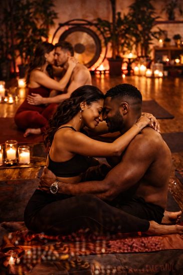 Two couples embracing intimately in a candlelit, cozy setting.