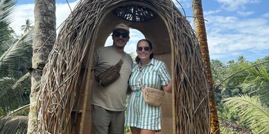 Couple posing inside a woven nest structure outdoors.