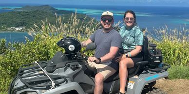 Couple riding ATV with scenic ocean view.
