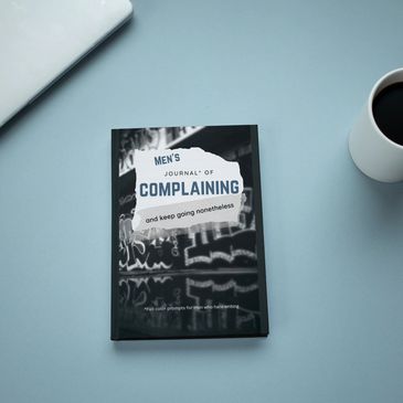 The Men's Journal of Complaining on a desk next to a laptop and a cup of black coffee.