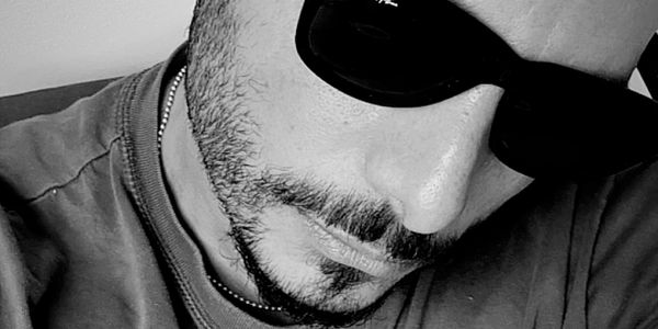 Close-up black and white photo of a man wearing sunglasses.