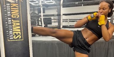Woman practicing a high kick in a boxing gym.