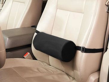 Almohada lumbar negra en asiento de coche beige.