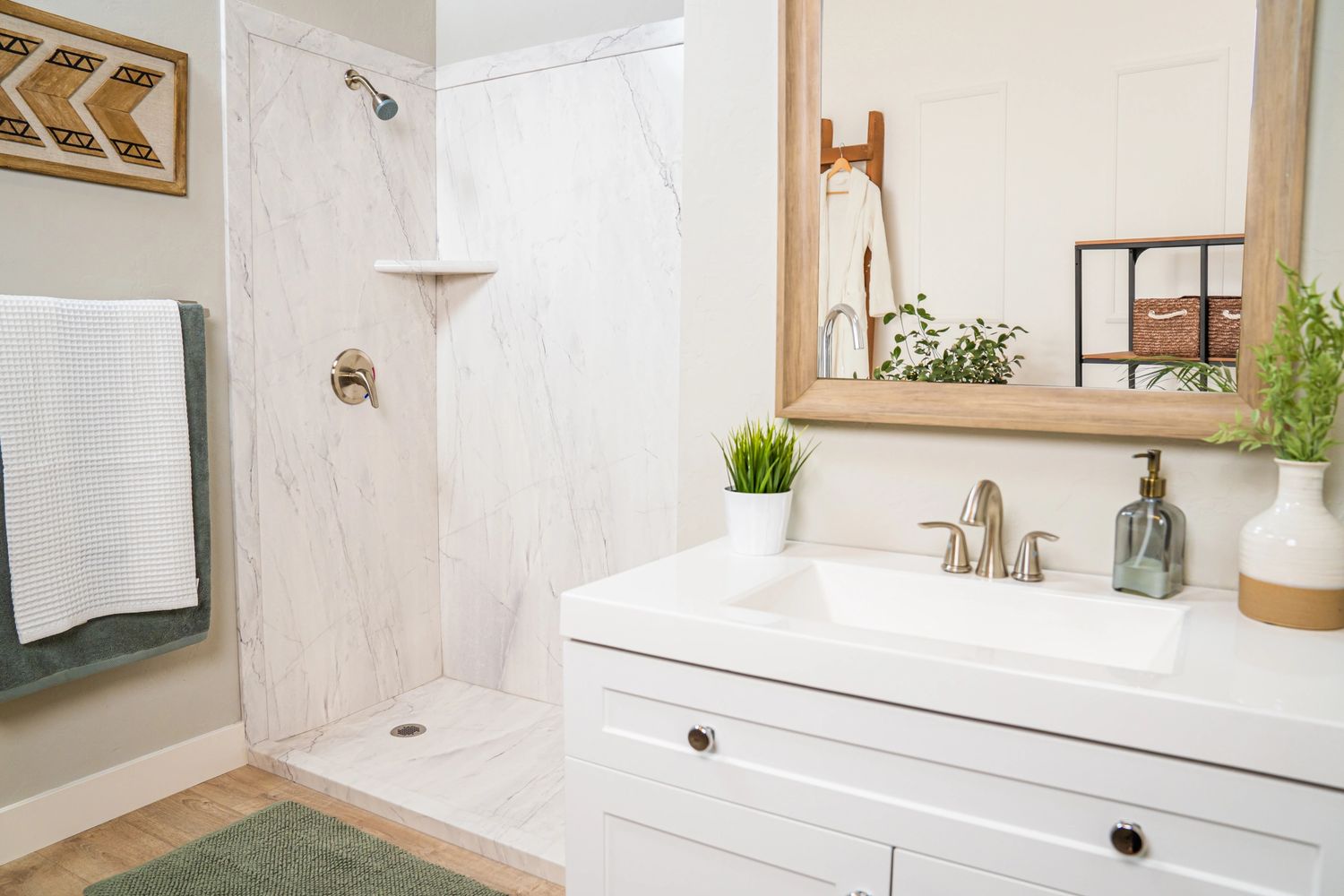Modern bathroom with white marble shower and wooden framed mirror.