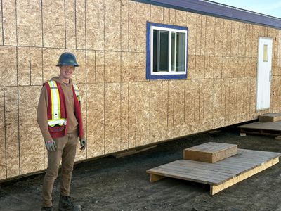 Construction worker posing by unfinished building.