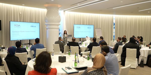 A professional seminar with attendees listening to a speaker in a conference room.