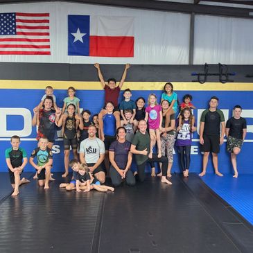 Group of kids and adults posing in martial arts gym.