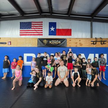 Group of kids and adults posing in a gym with flags.