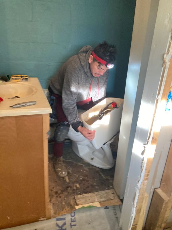A man removes the old toilet from the bathroom.
