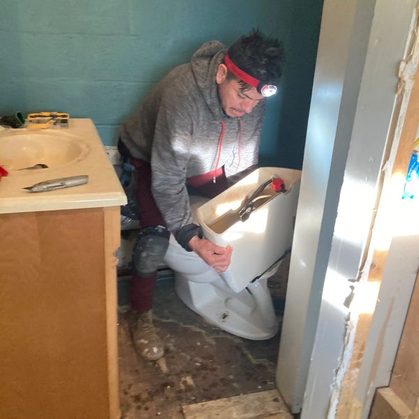 A man removing an old toilet from a bathroom.