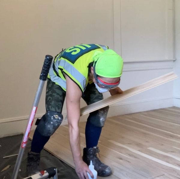 A woman wearing an AFO brace installs floors.